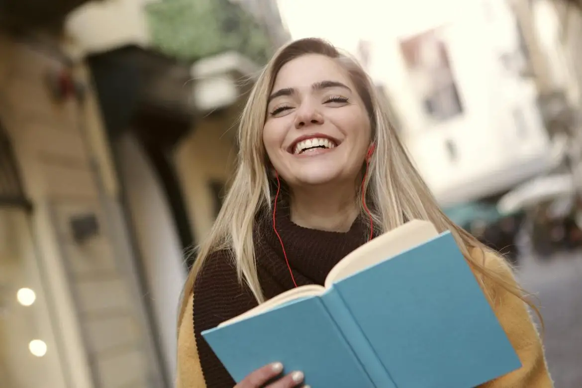 Photo by Andrea Piacquadio Smiling Woman in Black and Yellow Long Sleeve Shirt Holding Blue Book