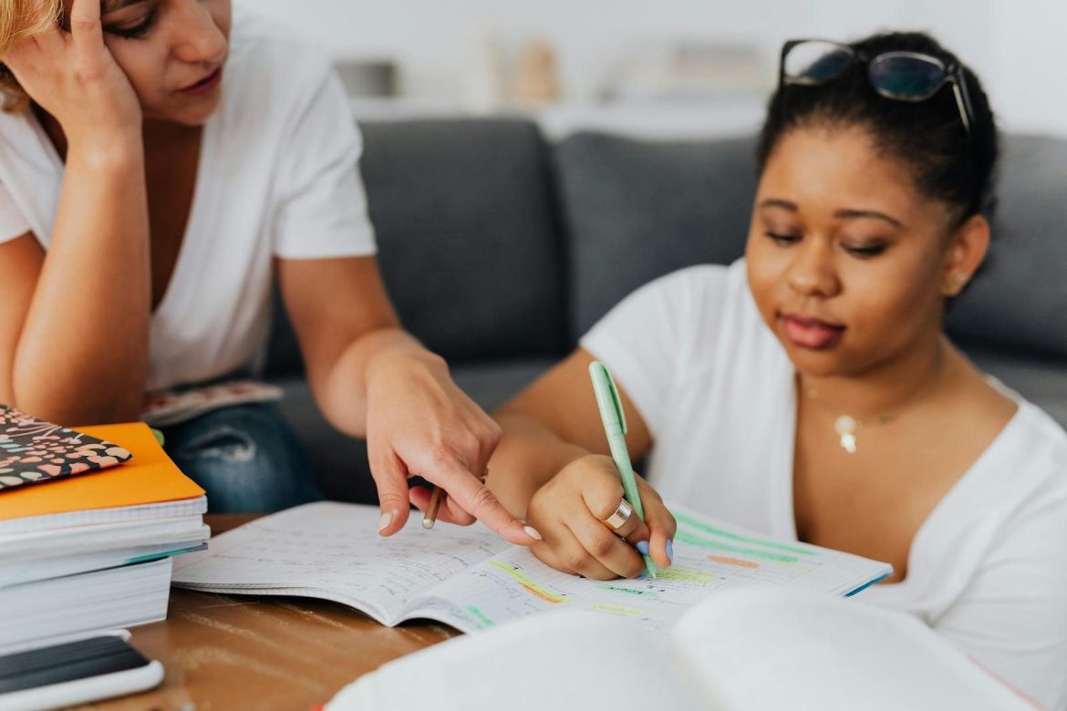 Two women studying with notebooks and pens in a tutoring session.